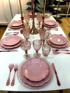 the table is set with pink plates and silverware