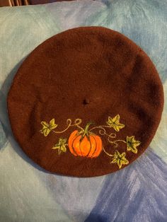 a brown hat with orange pumpkins on it sitting on top of a blue and white blanket