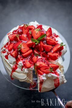 a cake with strawberries on top is being cut by a person holding a knife