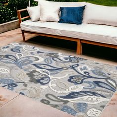 a couch sitting on top of a wooden floor next to a white rug covered in blue and gray flowers