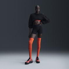 a woman in black and orange is standing with her hands on her hips while wearing knee high socks