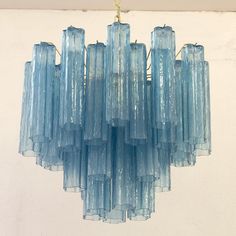 a chandelier made out of blue glass tubes hanging from a ceiling in a room