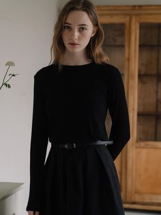 This top is characterized by its long sleeves and round neckline, offering a classic and versatile style. The hem is cut straight across, suggesting a neat finish when worn untucked. The material appears smooth and dense, possibly indicating a fine knit or a cotton blend that could provide both comfort and warmth. The clean lines and minimalistic style make it a foundational piece that can be paired with various types of bottoms and layered under other garments.- Its design is minimalistic, making it an essential piece that could be easily layered or worn on its own.- The darker shade allows for endless color coordination, making it a highly adaptable item for various fashion ensembles.- The simplicity of this top lies in its potential to be dressed up with statement jewelry or paired down Crew Neck Fine Knit Long Sleeve Top For Work, Workwear Fine Knit Long Sleeve Crew Neck Top, Fine Knit Long Sleeve Crew Neck Top For Work, Minimalist Long Sleeve Solid Top, Minimalist Black Top For Fall, Classic Long Sleeve Tops With Minimal Stretch, Classic Crew Neck Long Sleeve Top For Spring, Classic Crew Neck Long Sleeve Top For Fall, Classic Stretch Long Sleeve Top With Crew Neck