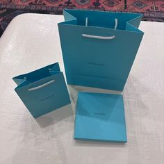 two blue shopping bags sitting on top of a table