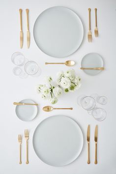 the table is set with white flowers and goldware