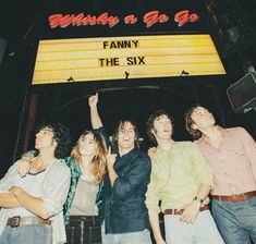 a group of people standing next to each other in front of a sign that says family the six