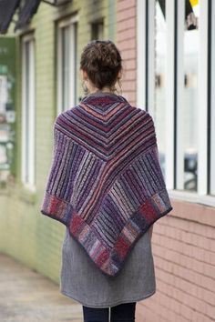 a woman is walking down the sidewalk wearing a shawl