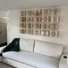 a white couch sitting in front of a wall with pictures on the wall behind it