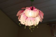 a pink flower hanging from the ceiling in a room with a green plant on it