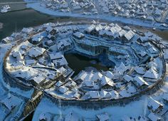 an aerial view of a snow covered city with lots of buildings in the foreground