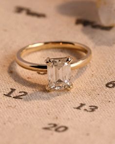 an engagement ring sitting on top of a piece of paper with numbers in the background