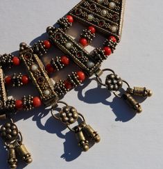 "1960's Southeast Asian vintage brass necklace with glass beading and brass dangles. 16\" total made to rest on your upper neckline or choker style. The orange beads are throughout and there are white blueish and red glass beads set in the long bars, there are 7 dandles at the bottom and all have a double bar of wrapped brass wire and attachments. All of the glass beads are in place and the thickness is 1/4\" and the main piece measures 1 3/4\" (not including the dangles) and a curved 8\" long." Vintage Red Jewelry With Dangling Beads, Vintage Metal Necklaces With Dangling Beads, Vintage Metal Necklace With Dangling Beads, Vintage Brass Beaded Necklace With Round Beads, Vintage Bronze Beaded Necklaces With Large Beads, Vintage Bronze Beaded Necklace With Large Beads, Vintage Adjustable Jewelry With Dangling Beads, Vintage Necklace With Dangling Beads For Festive Occasions, Vintage Bronze Beaded Brass Necklaces