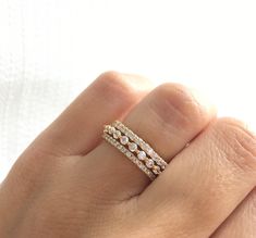 a woman's hand wearing a gold ring with three rows of diamonds on it