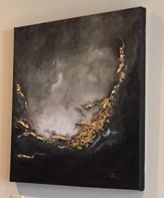 a black and gold painting hanging on the wall next to a white toilet paper dispenser