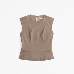 Versatile top in a lightweight suiting fabric and tailored fit, with corset-style seaming details along the bodice, front pockets, curved hem, back keyhole detail and trendy high-neck detail.