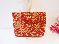 "Red handbag with lots of glamour. The background is red taffeta. The front of bag is embroidered with gold and white metallic threads. Beautiful vibrant color. The bag has a cream interior with a zipper closure. The back of the bag is solid red. This is a soft-side bag big enough to hold an iPhone. The interior of the bag is black. This is a beautiful bag for your wardrobe. MATERIAL: Taffeta, embroidery CONDITION: Good SIZE: 9\" x 7\" x 1 1/2\" COLOR: Red, gold, white" Red Shoulder Bag For Festive Gift, Festive Red Shoulder Bag As Gift, Festive Red Shoulder Bag For Gifts, Red Rectangular Evening Bag For Festivals, Red Embroidered Party Bag, Red Embroidered Party Bags, Red Evening Bag With Handwork For Gifts, Red Shoulder Bag For Party And Festivals, Red Rectangular Evening Bag For Festive Occasions