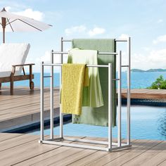 two towels are hanging on a towel rack next to a swimming pool with an umbrella