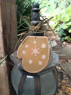 an old fashioned lantern with a tag hanging from it's side in front of some plants