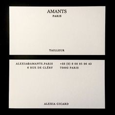 two white business cards sitting on top of each other in front of a black background