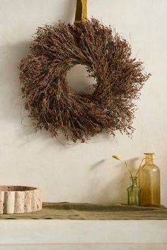 a wreath hangs on the wall above a mantle