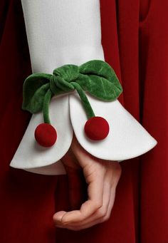 a person in a red dress holding onto a white object with green leaves on it