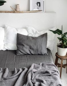 a bed that has some pillows on top of it and two plants in the corner