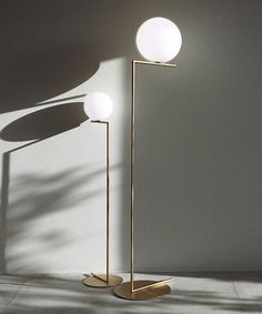 two floor lamps in the corner of a room with shadows on the wall behind them