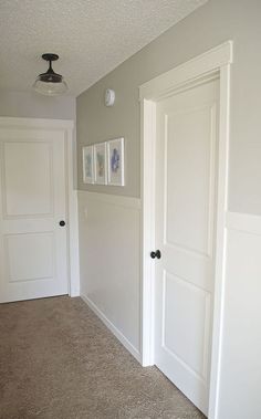 an empty room with two doors and pictures on the wall