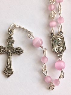 Handmade with small 4mm and 6mm pink cats eye beads and silver metal wire. I love the cats eye beads because of the ribbon of light that appears and follows the sun. Small Our Lady of Fatima medal and small crucifix. Comes with a gift pouch Pink Spiritual Rosary Bracelet With 8mm Beads, Pink 8mm Bead Spiritual Rosary Bracelet, Handmade Pink Rosary For First Communion, Pink Rosary For First Communion, Pink 8mm Beads Rosary Bracelet, Affordable Pink Rosary Gift, Pink Rosary With Miraculous Medal As A Gift, Pink Rosary With Round Beads For First Communion, Handmade Pink Cross Rosary