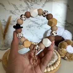 a person holding onto a bracelet made out of wooden beads and wood beads, with two teddy bears in the background