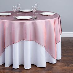 the table is set with white plates and silverware, along with pink napkins