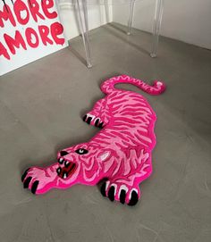 a pink stuffed animal laying on the floor in front of a sign that says more amore