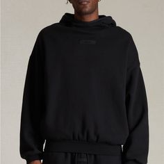 The Fear Of God Essentials Jet Black Hoodie Features An Oversized Fit, A Mock Neckline, Long Sleeves, Side Seam Pockets, An Attached Hood, Contrast Stretch Binding, And Rubber Brand Labels At The Center Front And Upper Back. Solid Color Hoodie Attached Hood Long Sleeves Mock Neckline Dropped Shoulders Side Hand Pockets Front & Back Rubber Brand Labels Contrast Stretch Binding Relaxed Fit 80% Cotton, 20% Polyester Brushed Back Fleece Hand Wash, Flat Or Line Dry Streetwear Funnel Neck Hoodie With Adjustable Hood, Black Hoodie With Double-lined Hood For Loungewear, Funnel Neck Hoodie With Adjustable Hood For Streetwear, Oversized Hoodie With Ribbed Cuffs And Funnel Neck, Sporty Hoodie With Relaxed Fit And Funnel Neck, Sporty Relaxed Fit Hoodie With Funnel Neck, Black Double-lined Hoodie For Loungewear, Urban Hoodie With Funnel Neck For Streetwear, Black Hoodie With Drawstring For Loungewear