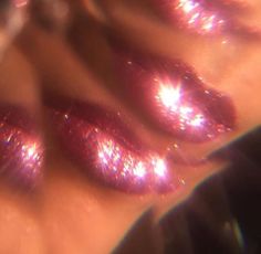 some shiny pink nail polishes on someone's hand