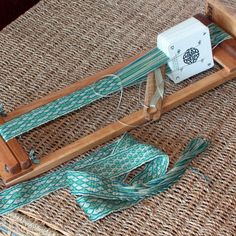 an old weaving loom sitting on top of a wicker table next to a piece of cloth