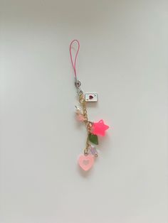 a cell phone charm with charms attached to it on a white surface and a camera in the background