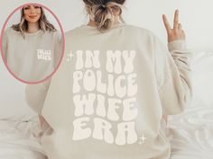 ✨ The perfect trendy vibe for a stylish police wife! It's made from a soft, midweight cotton blend fabric for easy layering when it's chilly or alone for comfort. It makes a great gift for the police wife in your life! We think this cozy sweatshirt has all the qualities a police wife could want when supporting her Airman!  ✨ All items are made to order. They will ship within one week from one of our print partners. Please allow sufficient time for production and shipping.  ✨ Our designs are printed using the highest quality professional DTG (direct to garment) printing process, which means fabric-grade ink is printed directly onto the garment and blends with the fibers. This allows us to achieve a vintage style look on many of our designs, and a feel that is similar to screen printing, and Fire Wife Shirt, Police Officer Girlfriend, Cop Wife, Wife Sweatshirt, Law Enforcement Gifts, Paramedic Gifts, Fire Wife, Mrs Sweatshirt, Medical Technician