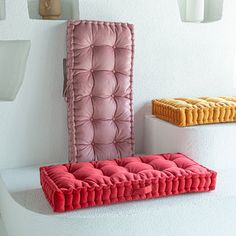 two different colored cushions sitting on top of each other in front of a white wall