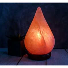 an orange himalayan stone lamp sitting on top of a wooden table next to a potted plant