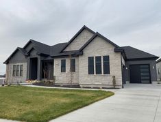 a house that is in the middle of a grass area with two garages on each side