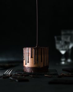 a chocolate cake sitting on top of a table next to a glass filled with liquid