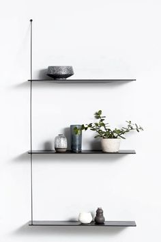 three black shelves with plants and vases on them