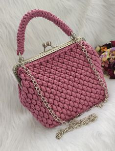 a pink crocheted handbag sitting on top of a white furnishing