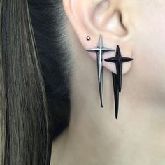 two pairs of black and silver earrings on the back of a woman's ear