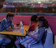 three people sitting at a table with cell phones