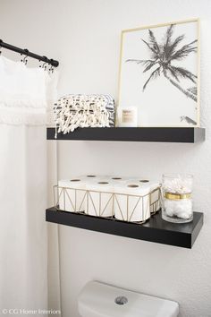 two black shelves above a toilet in a bathroom