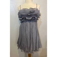 a mannequin wearing a gray dress with ruffles on the bottom and sides