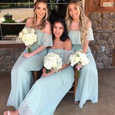 three bridesmaids sitting on a chair with bouquets in their hands and smiling at the camera