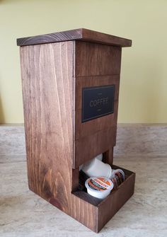 a wooden box with coffee cups in it on a counter top next to a wall