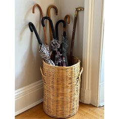 several umbrellas are placed in a basket on the floor